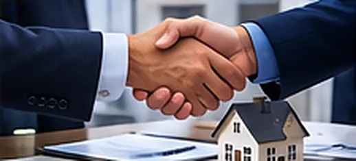 Two people shaking hands over a home purchase agreement